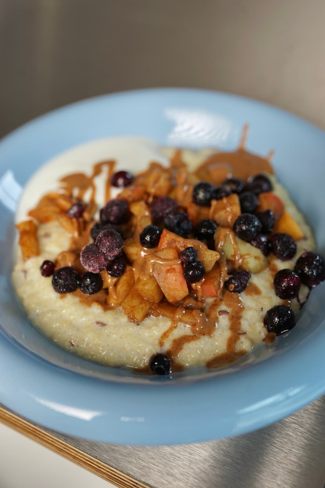 Hirse-Protein-Porridge mit Zimtapfel, Wildheidelbeeren und Mandelmus in Nahaufnahme