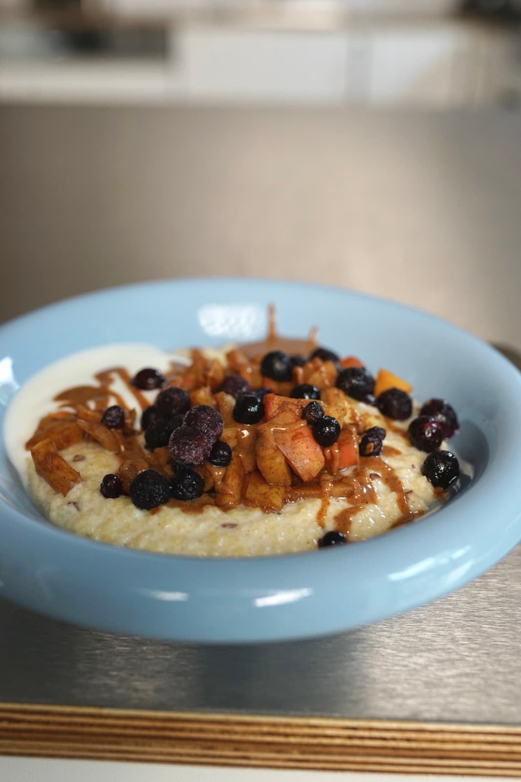 Hirse-Protein-Porridge mit Apfel und Wildheidelbeeren in einer blauen Schale