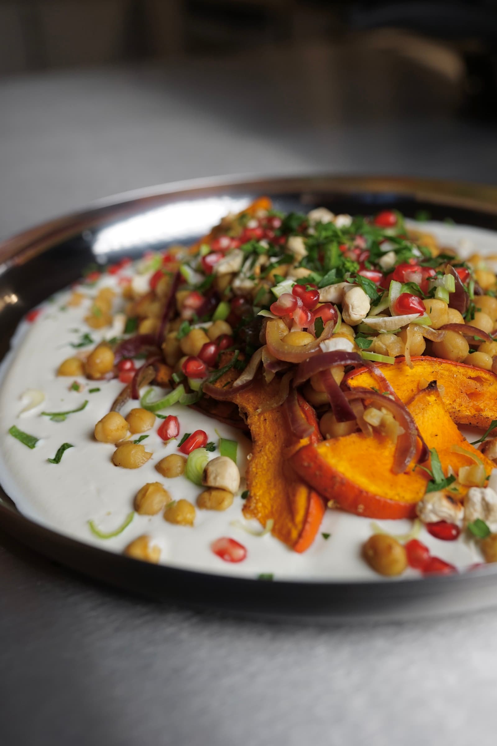 Nahaufnahme von Ofenkürbis auf Tahini-Joghurt mit Butter-Kichererbsen, Granatapfel und Cashews