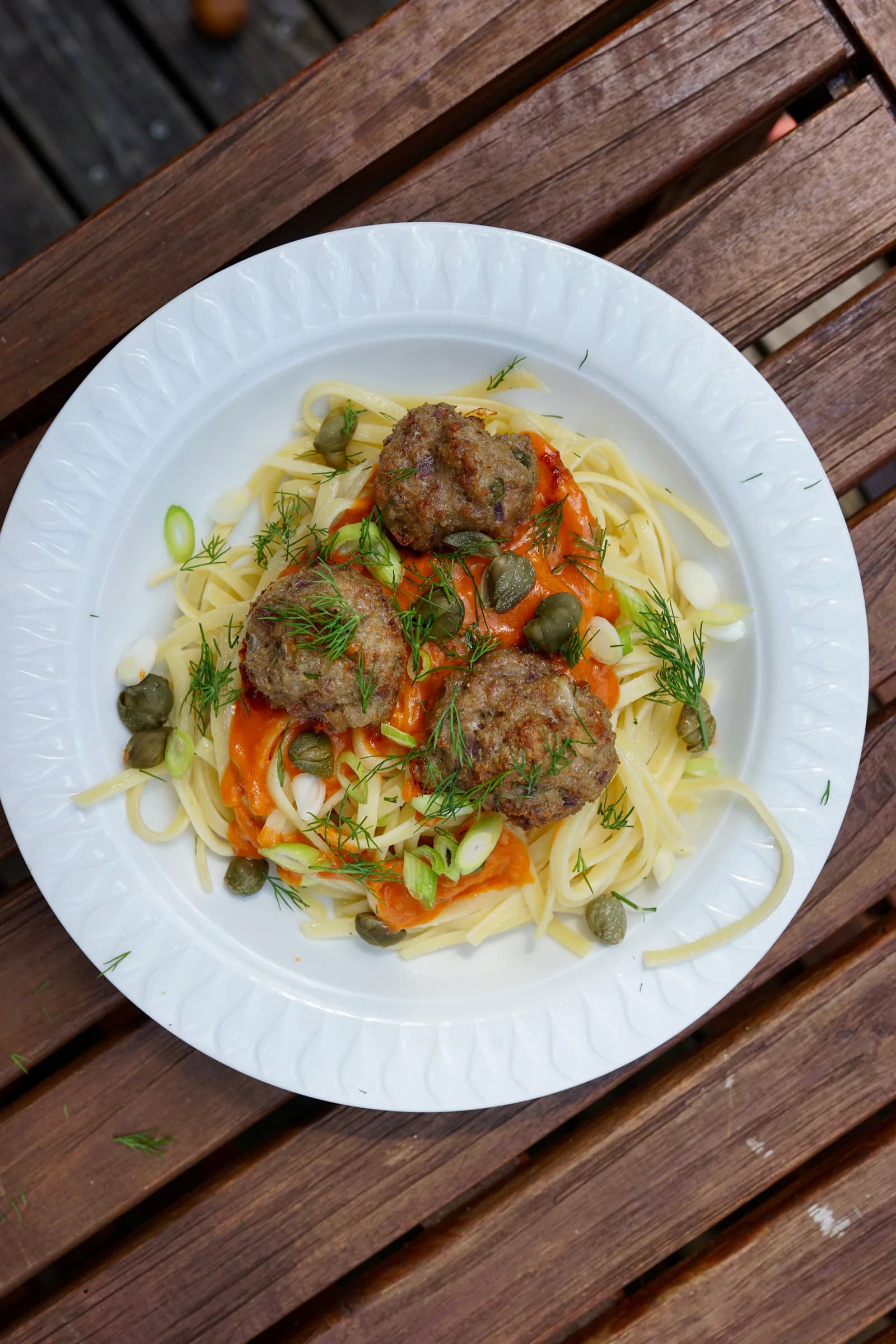 Spaghetti mit Ricotta-Meatballs, cremiger Pesto-Rosso-Soße, Dill und Kapern aus der Draufsicht