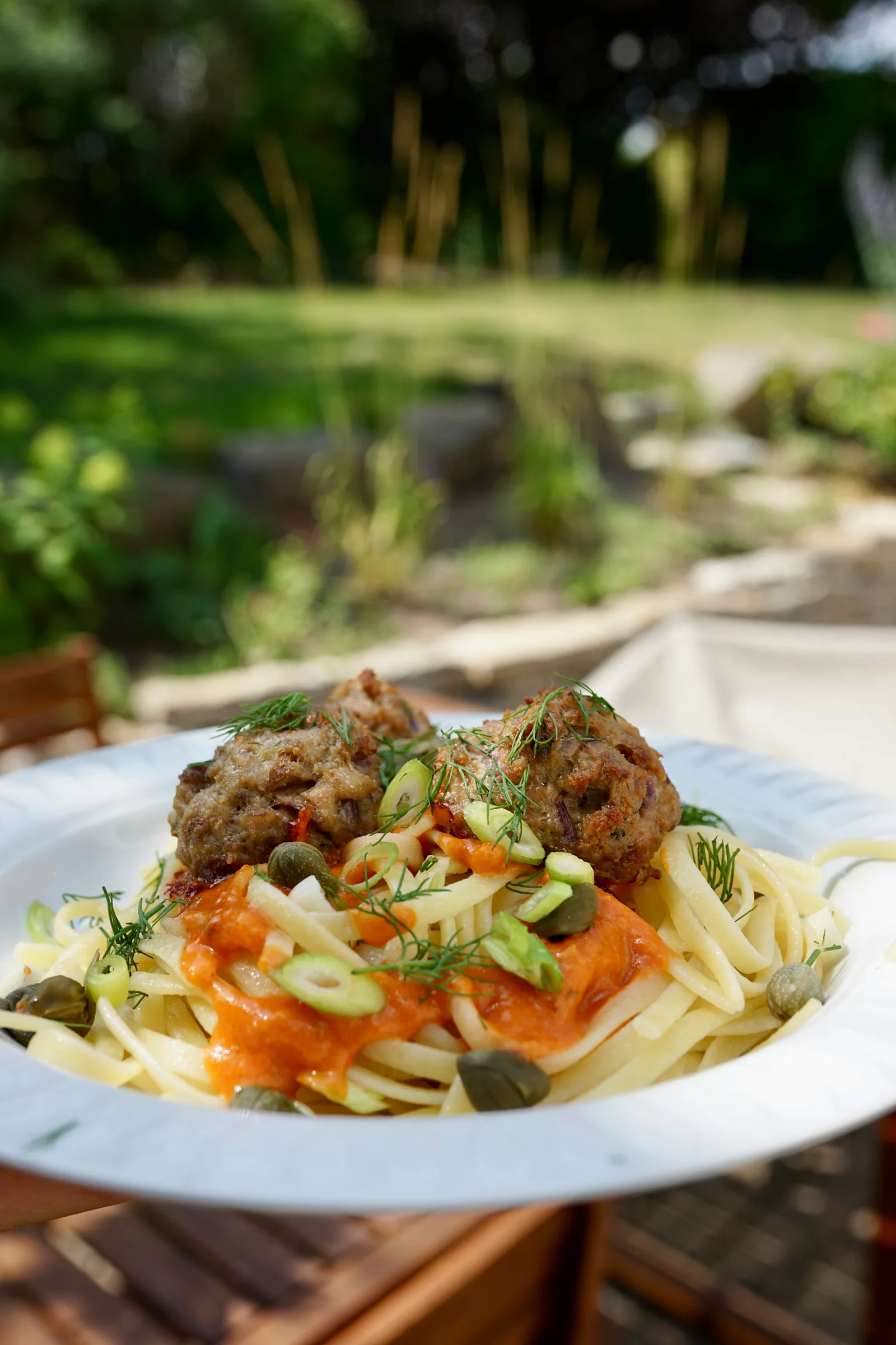 Servierter Teller Spaghetti mit Ricotta-Meatballs, Dill, Frühlingszwiebeln und Kapern