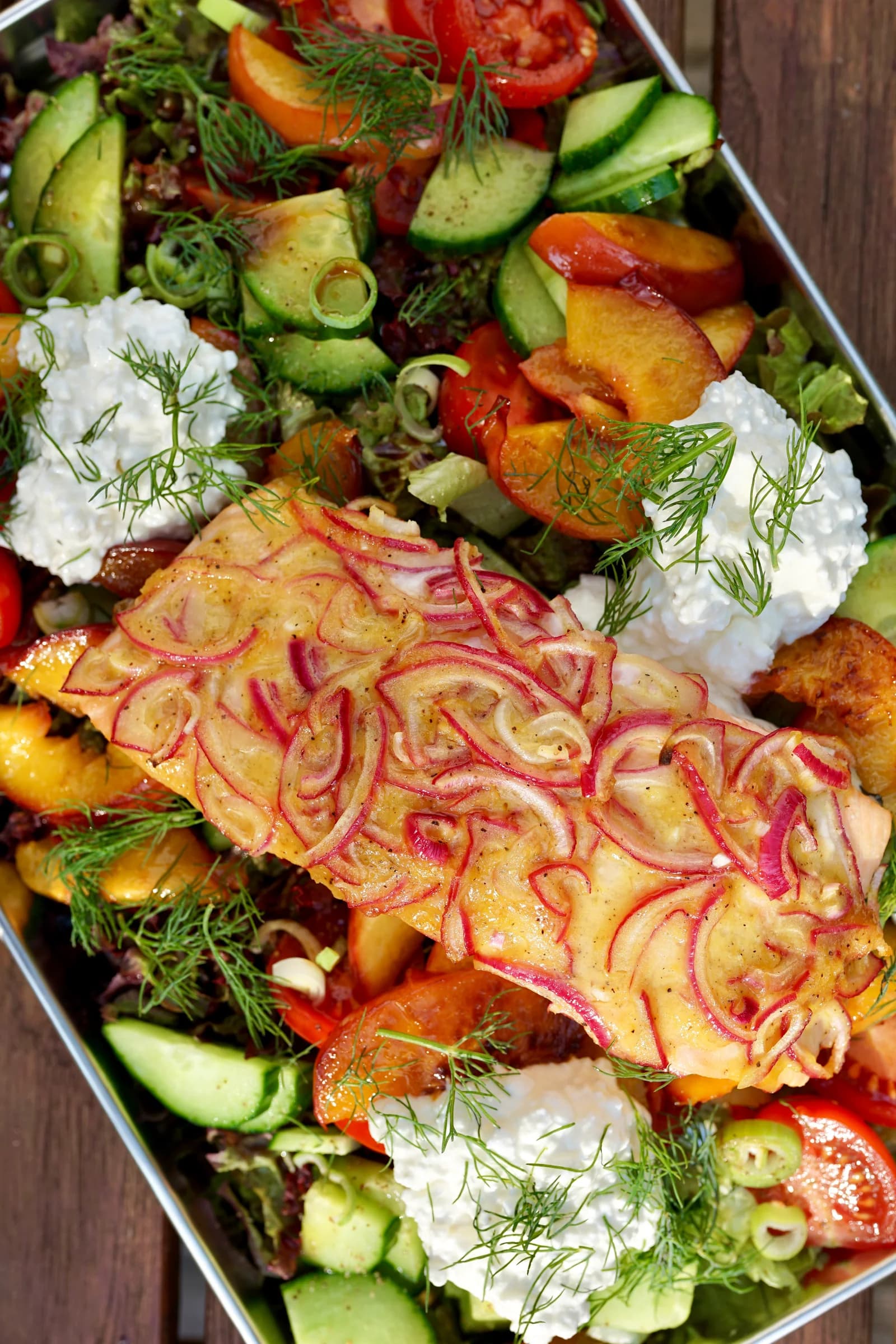 Nahaufnahme von Honig-Senf-Lachs mit roten Zwiebeln, Nektarinen und Salat